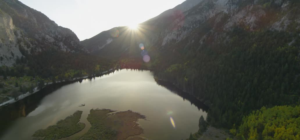 Valley lake surrounded by mountains at sunset