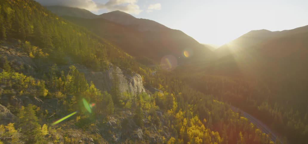 Range of mountains with trees while the sun goes down behind the mountains
