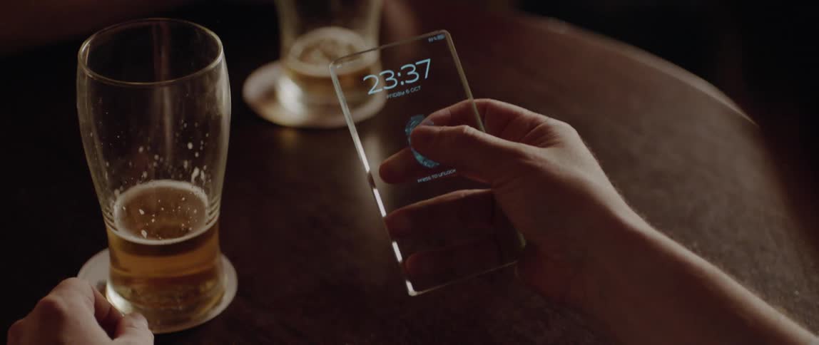 A person sitting at table uses their fingerprint to open a device
