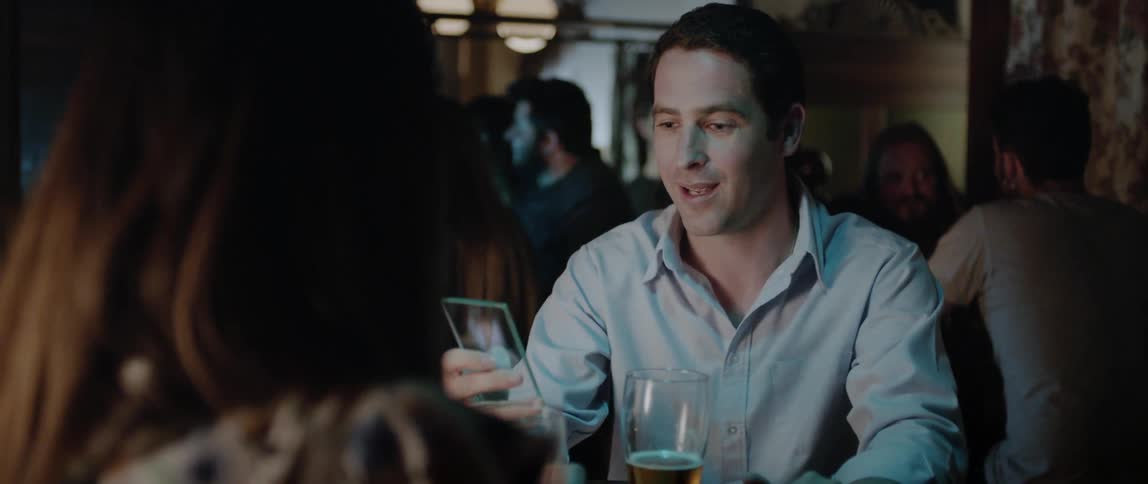 Man sitting at table at nightclub shows woman cell phone picture