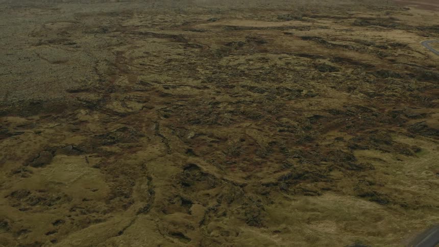 Road winds through rough terrain with mountains on the horizon