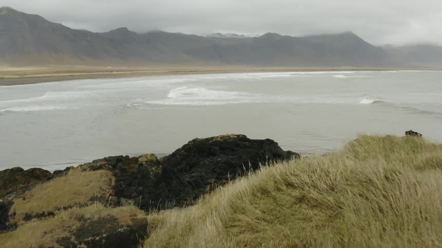 A field rocky coastline bay and mountains on a cloudy day