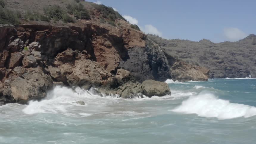 Blue ocean with waves crashing on rocky cliffs