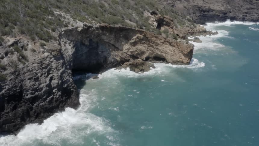 Waves crash against rocks at high sun