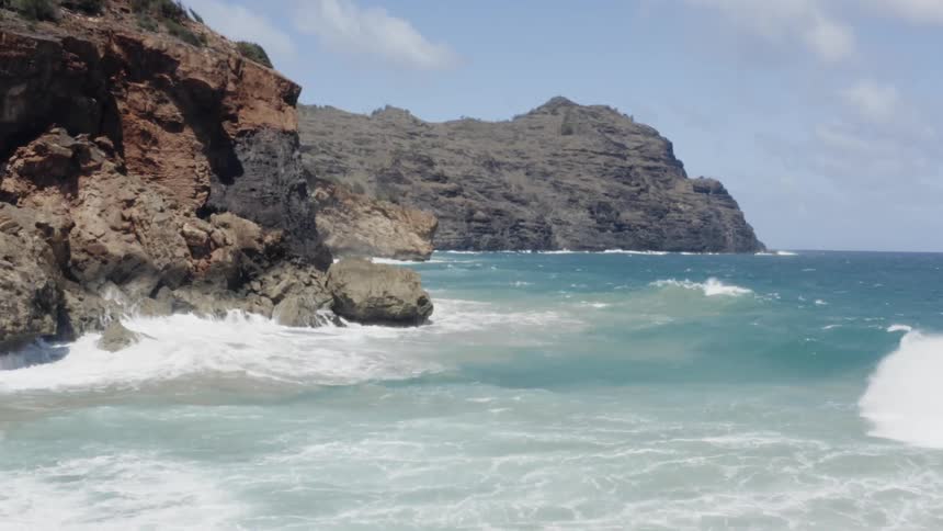 The beautiful blue ocean gives way to crashing waves that wash upon the rocking cliffs lining the shore