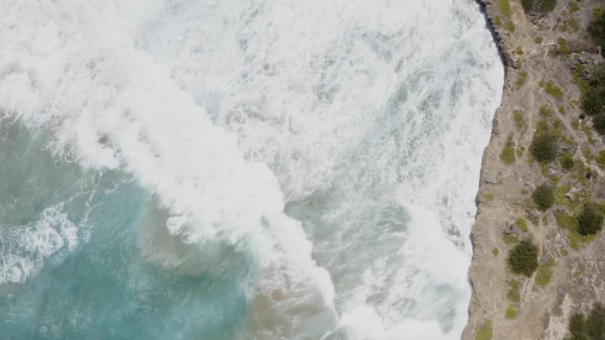 Turquoise ocean waves crash into a shoreline