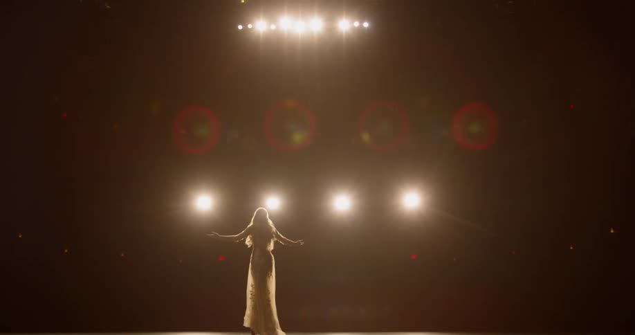 A woman performing on a bright lit stage