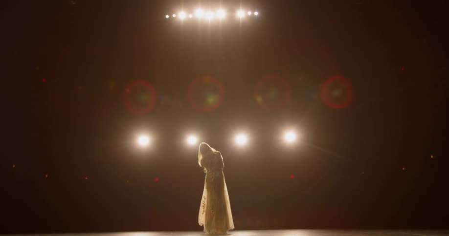 A woman wearing a white dress performing on a stage