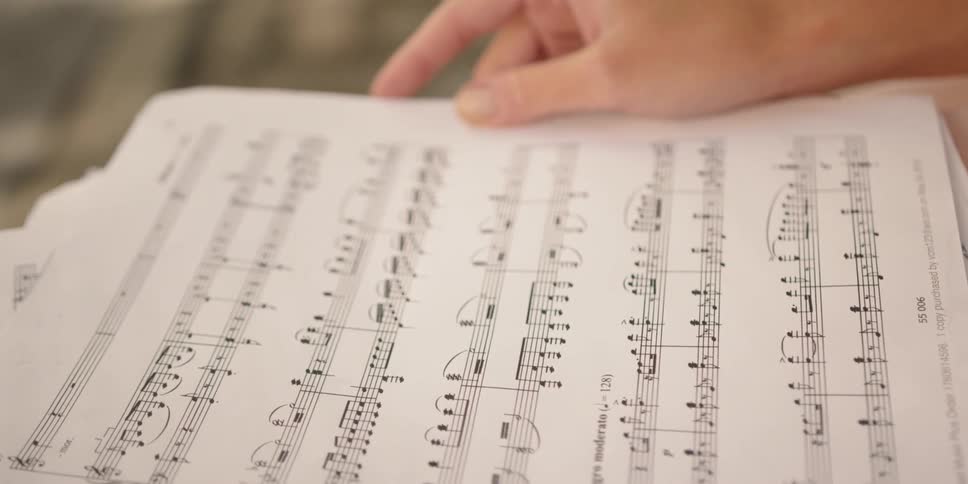 A woman in a dress reading sheet music in her lap