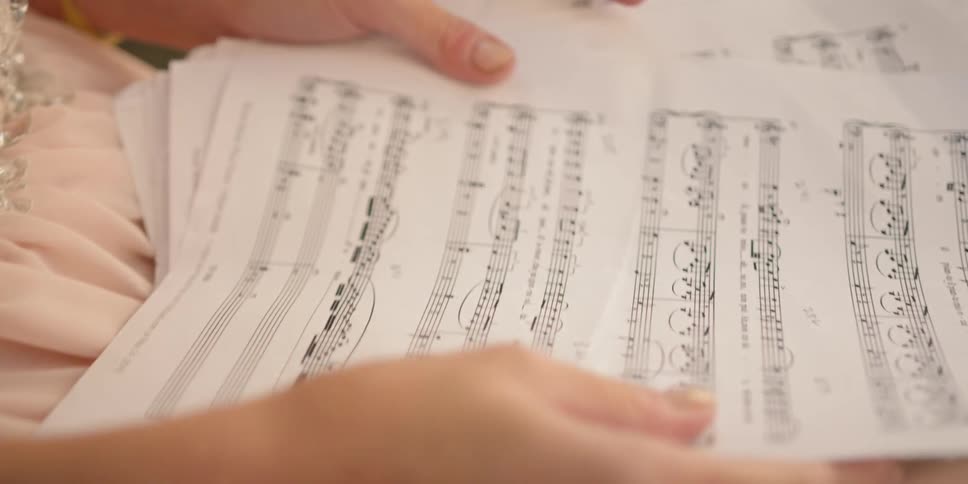 Woman holds several sheets of music in her hands