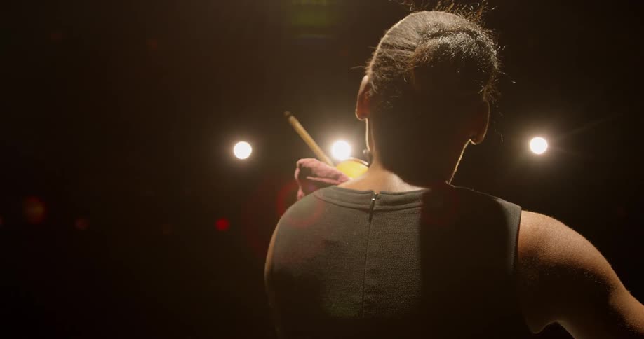 A view of the back of a woman while she plays a musical instrument