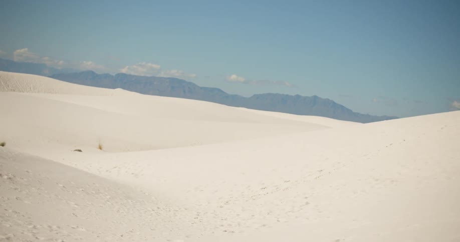 A large stretch of sand with a hilly area far off in the distance