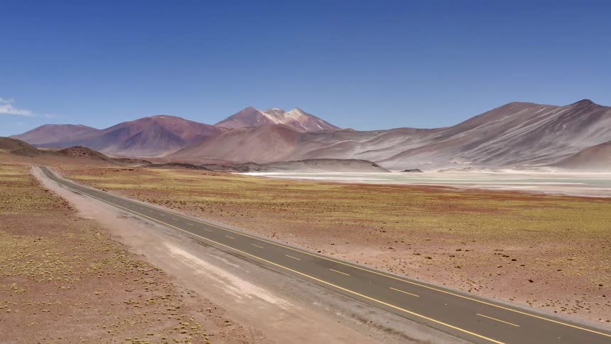 A rural road through an arid landscape with mountains in the distance