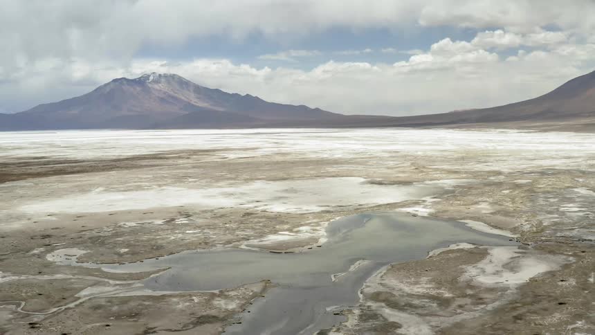 A salt flat extends to a mountain range in the distance