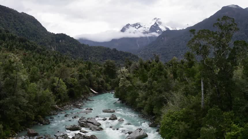 A river running through a wooded area near mountains