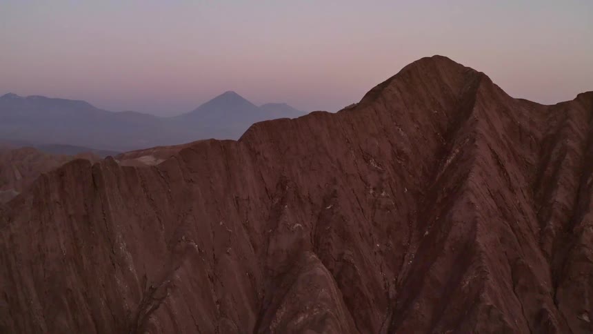 A jagged mountain range rises up with more mountains in the background