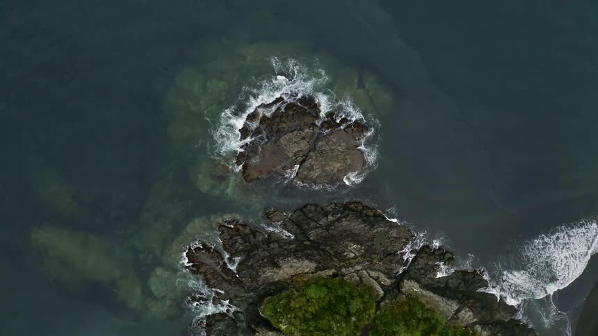 Slow moving aerial shot overlooking rocks in water