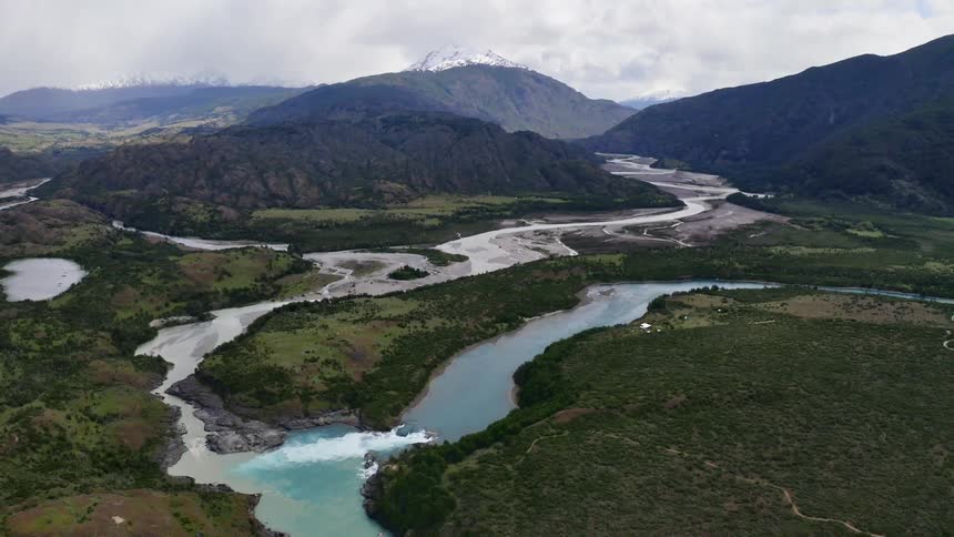 Rivers cut through the countryside with snow capped mountains in the background