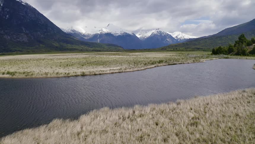 A river cuts through the country with mountains in the background