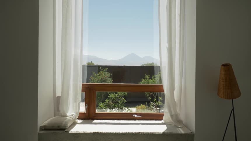 The inside of a home in a room with a window and open curtains