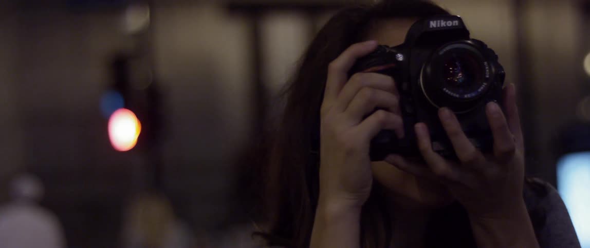 Brunette woman taking pictures in a city at night