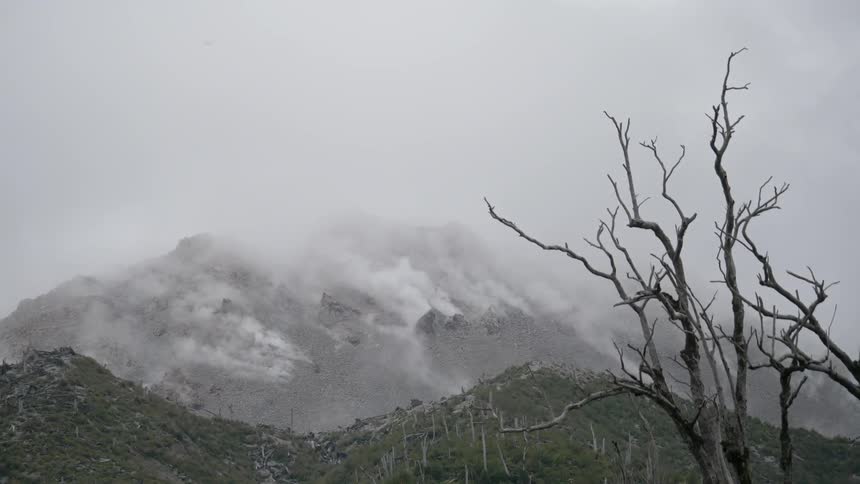 Fog rolls over a mountain on an overcast winter day