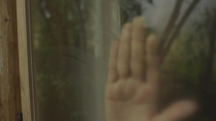 A woman wiping the dew off of the window