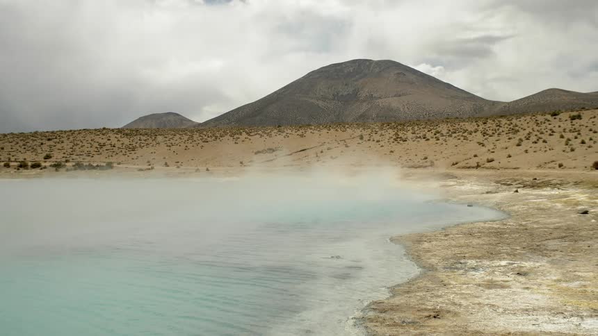 A lake can be seen in a desert area that has a mountain in the background