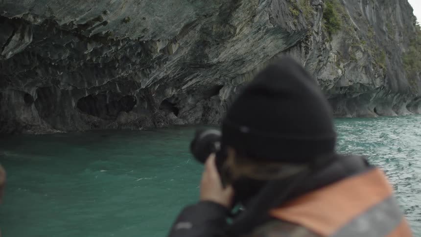 Photographer on boat takes photos of ocean cliffs