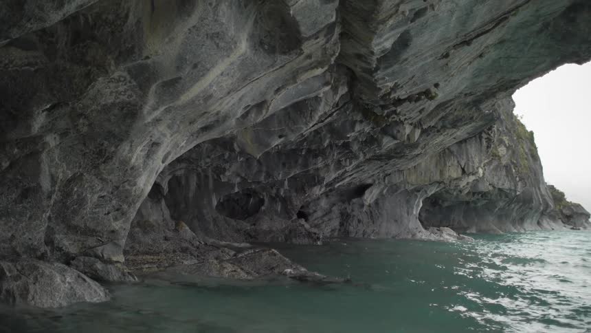 Ocean tide calmly falling against the bottom of a cliff
