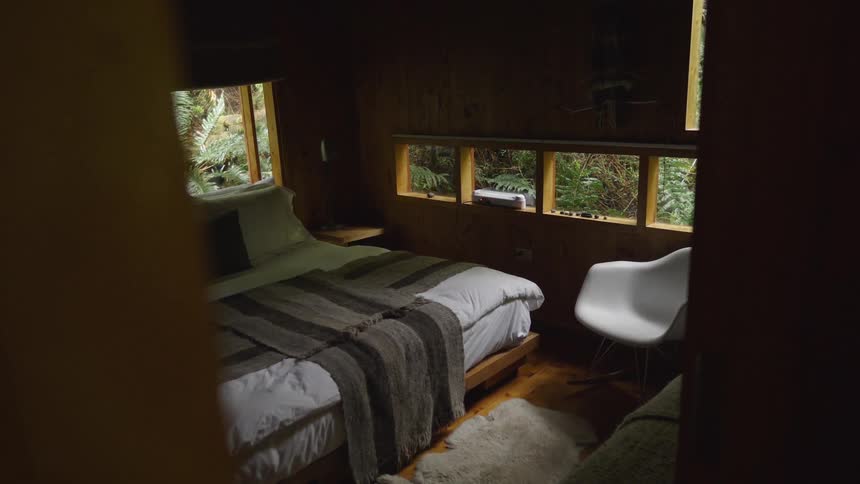 A large bed in a room with wooden walls and contemporary furniture