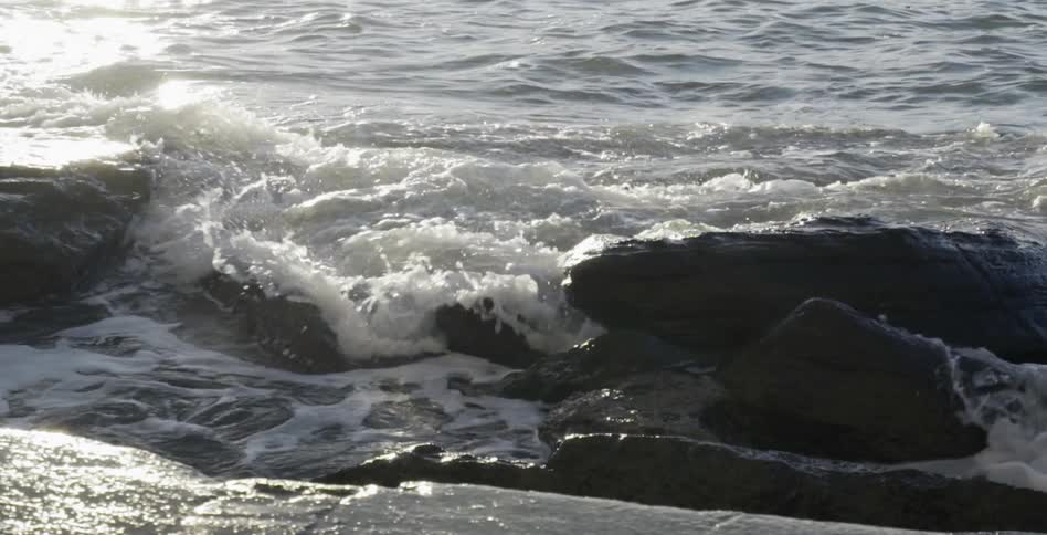 Waves crashing into rocks on a sunny day