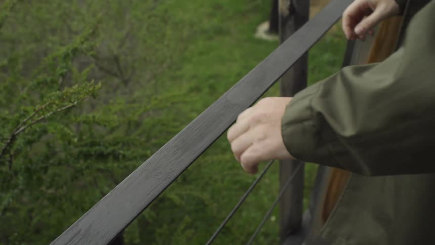 Wind blowing a branch next to a porch where a man walks up and grabs the rail
