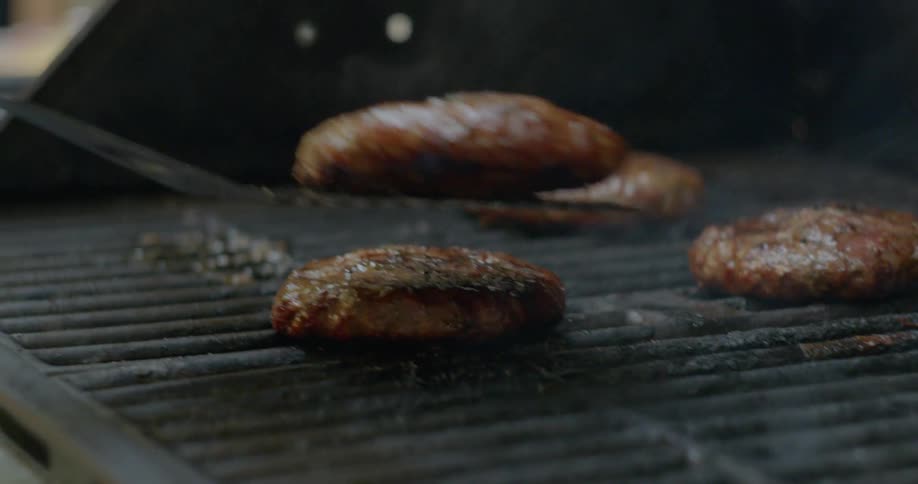 Burgers being cooked and moved on a grill