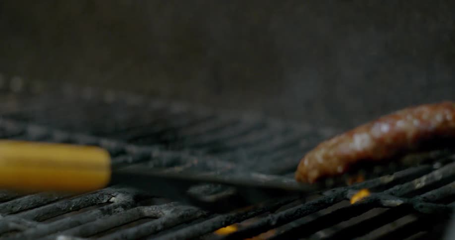 A spatula flipping a burger on a flaming grill