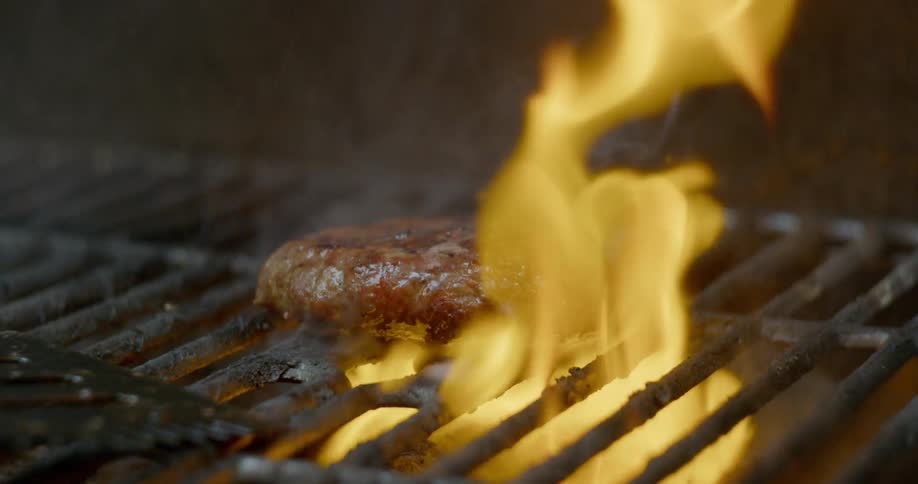 Burger cooks on fiery grill