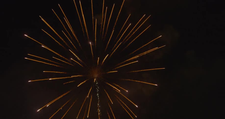 A firework shoots up into the night sky then explodes
