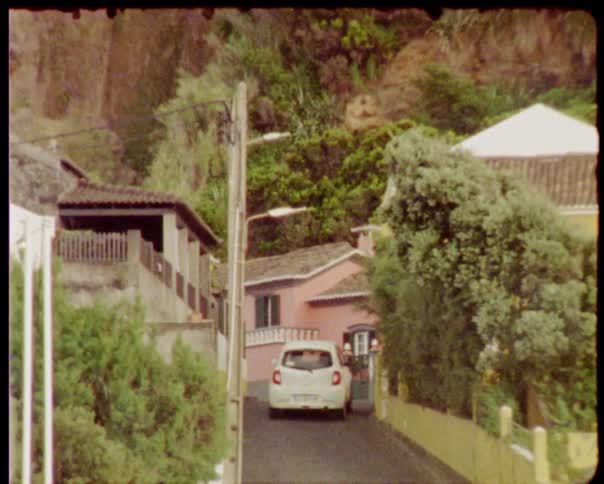 A small car driving down a narrow one way street
