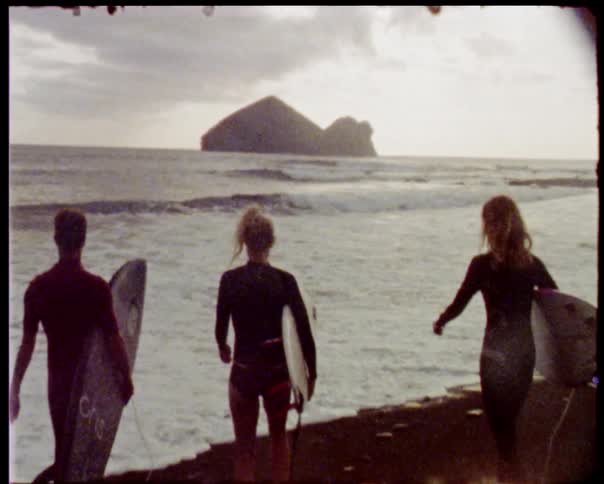 Surfers with boards approach water
