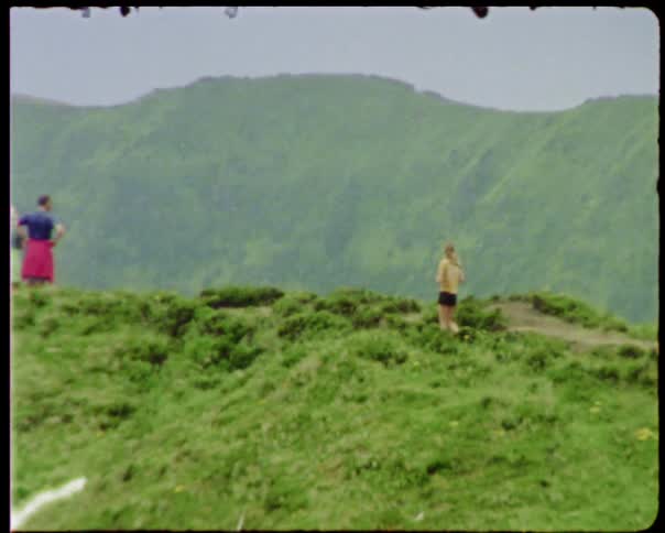 A woman on a hilltop walks towards a man