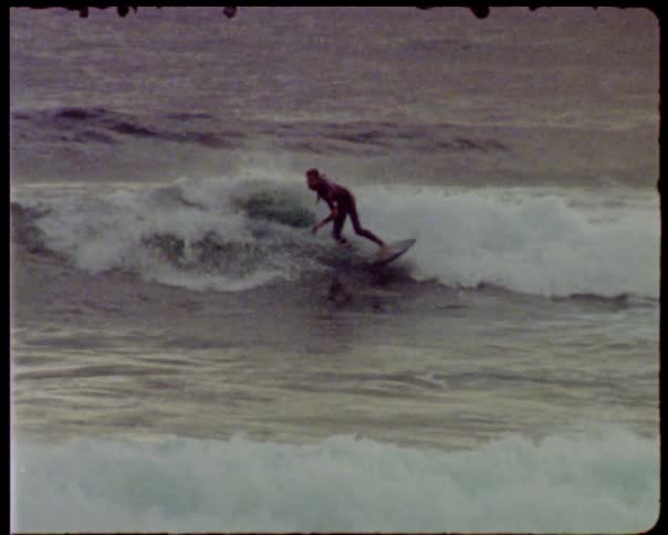 A male surfer rides a wave at sunset