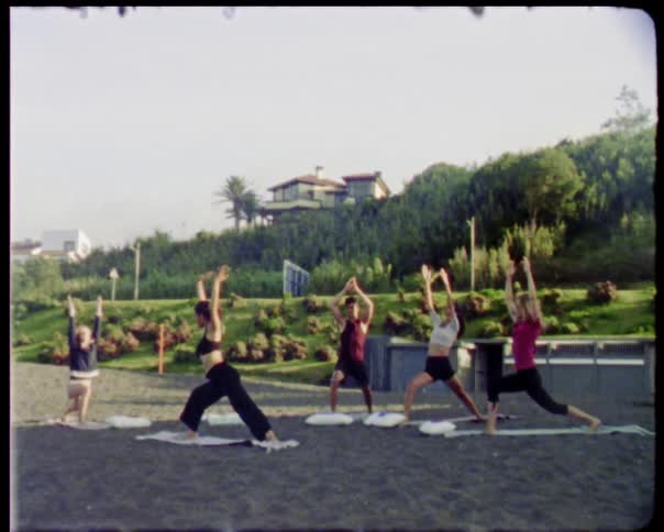 A group of people do yoga on the beach