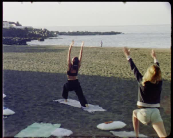 Woman leading a small group of people doing yoga on the beach