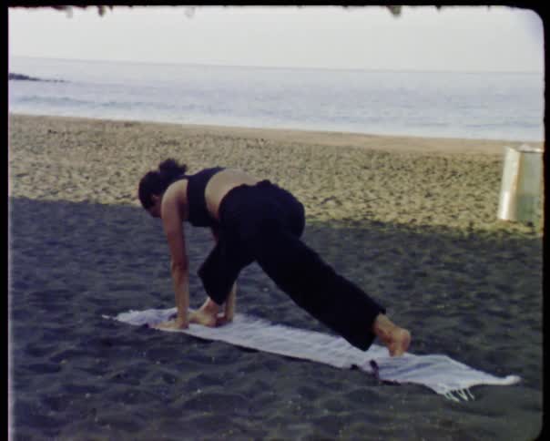 A woman is stretching on a beach