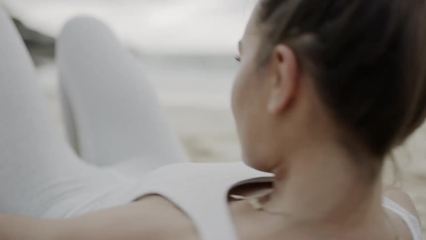 Woman warming up for exercise on the sand of a beach