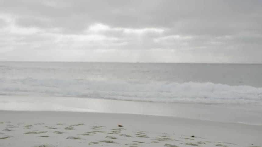 A white woman in exercise clothing doing exercises on a beach during the day
