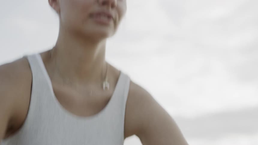 A white woman in exercise clothing doing squats outdoors during the day