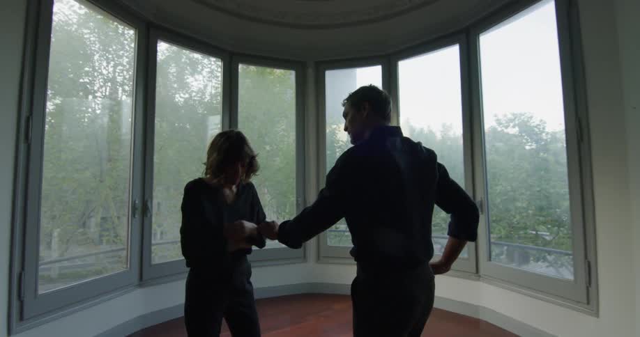 Couple arguing in a vacant round room while its raining outside