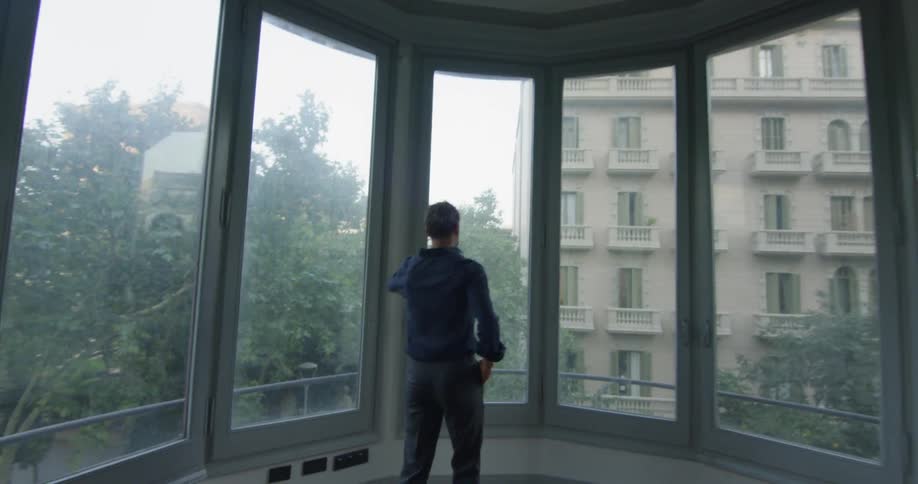 Man entering a room and looking out a balcony window