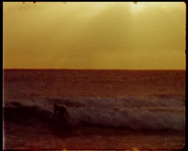 Man surfing wave on surfing board at sunset